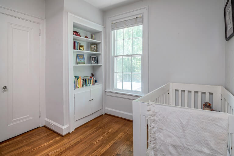 White themed baby room with crib and bookshelf