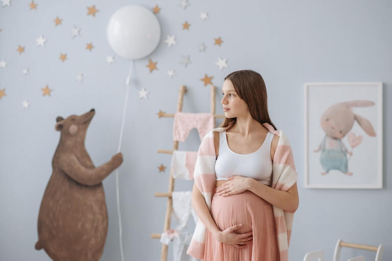 Pregnant mom standing in a baby nursery