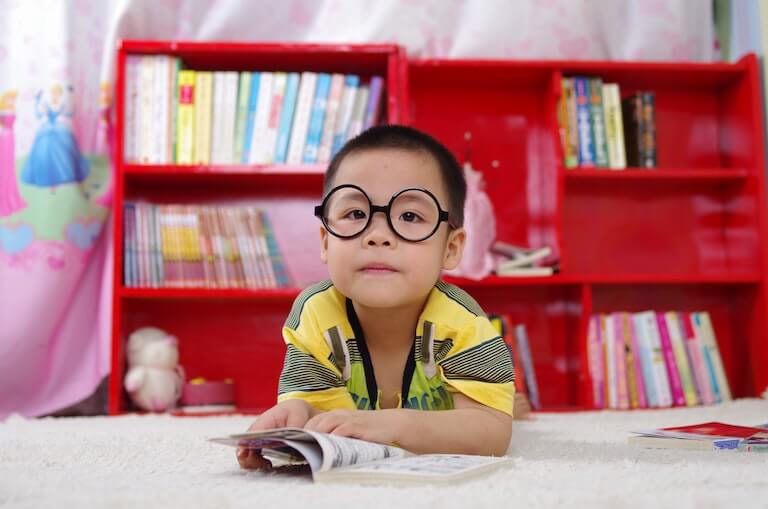 A child with glasses on reading a book