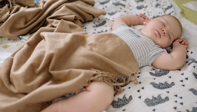 Baby in bed sleeping on their back