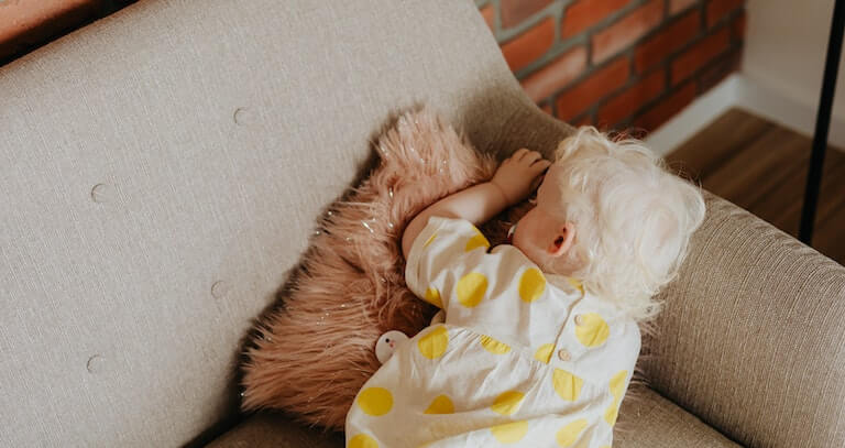 Baby sleeping on their stomach on the couch