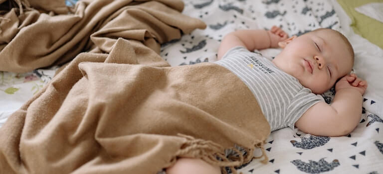 Baby sleeping in a bed with a blanket on