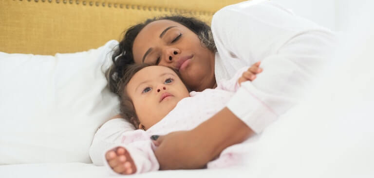 Mother and daughter sleeping together in bed