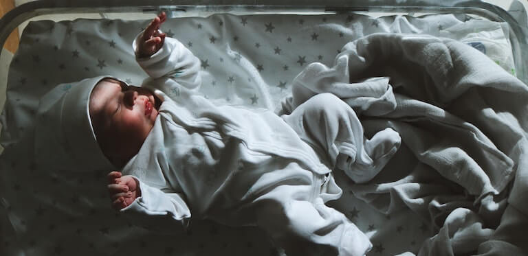 Newborn baby in a small bed asleep