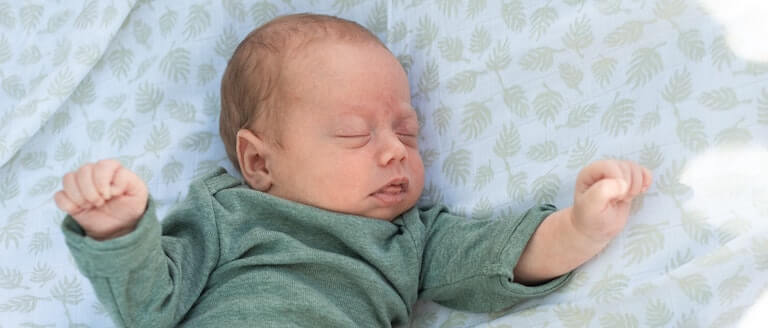Newborn baby in a large bed sleeping
