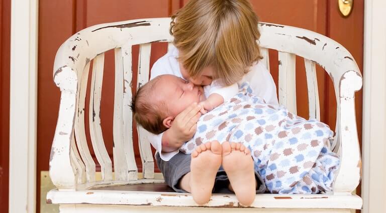 Older sibling kissing a newborn baby