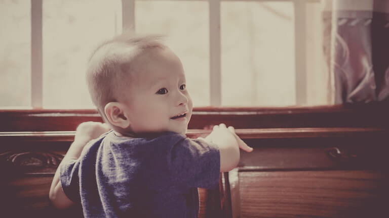 Baby crawling on a brown dresser