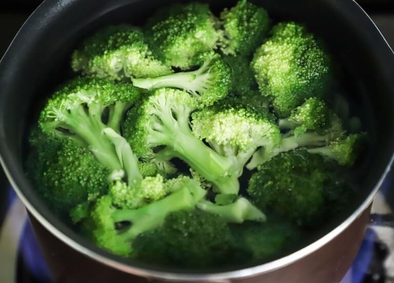Broccoli being cooked on a stove in a pot