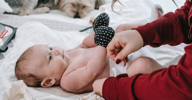 Baby being changed with a dog laying down nearby