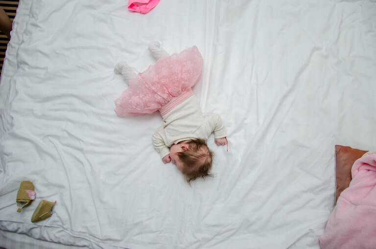 Baby girl in bed sleeping on her stomach