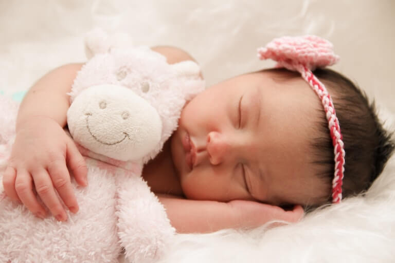 Baby girl sleeping with a stuffed animal