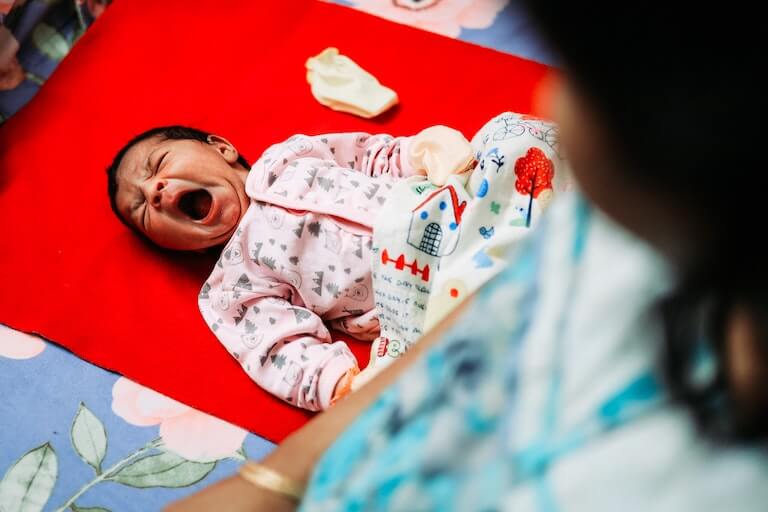 Baby girl on her back with mouth open wide
