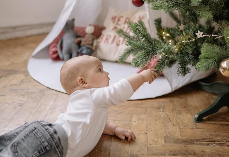 Baby on stomach grabbing the christmas tree