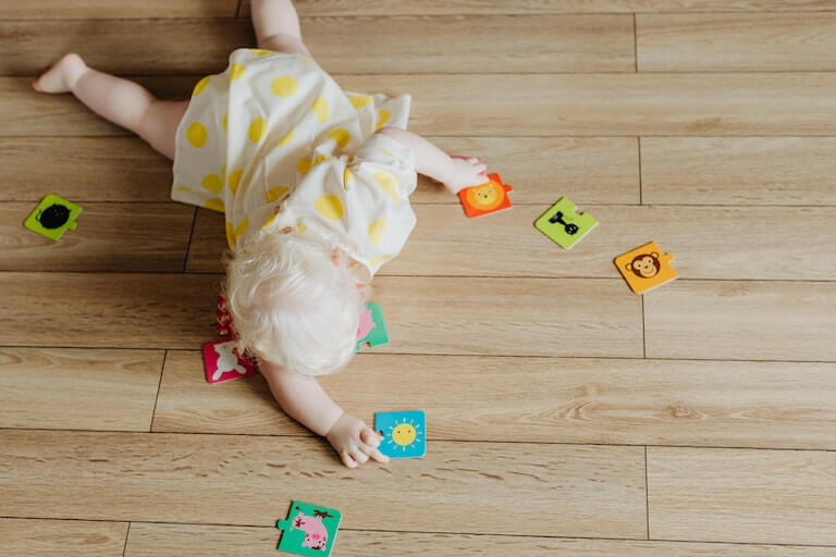 Girl crawling on the ground with toys around