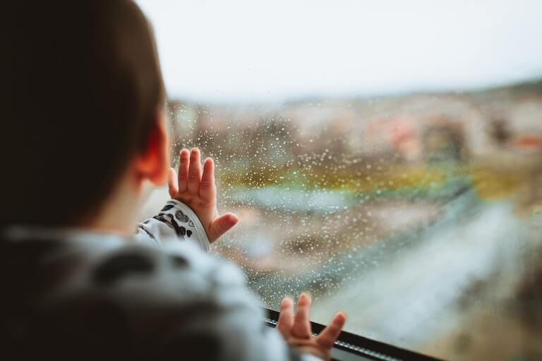 Baby with hand on train window looking outside