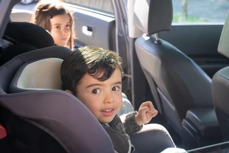 Little boy in a car seat with his sister next to him