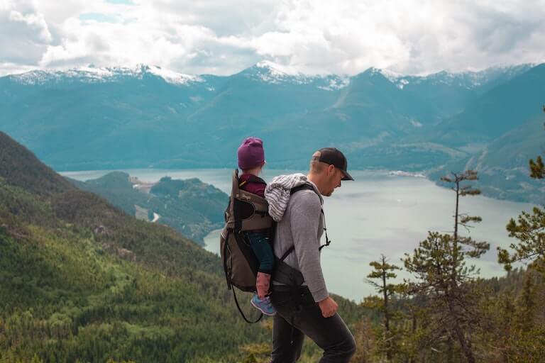 Father with his daughter on his back hiking in the mountains