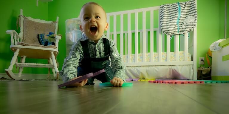 Baby boy on the floor playing with his mouth open