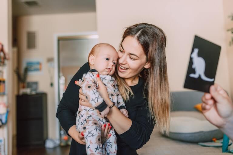 Mom teaching her newborn son what a kangaroo is with a flashcard