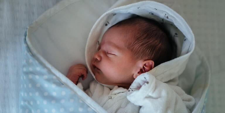 Newborn baby in blue outfit sleeping