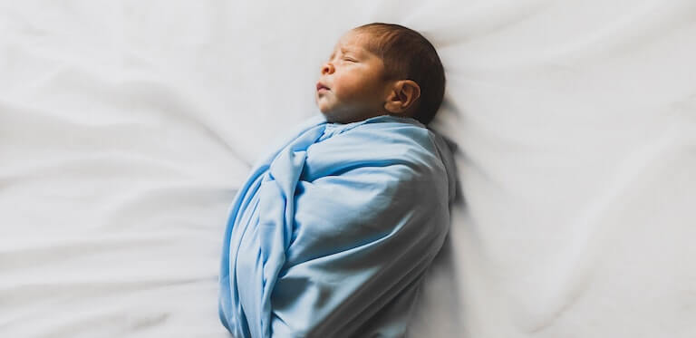 Newborn baby swaddled in blue