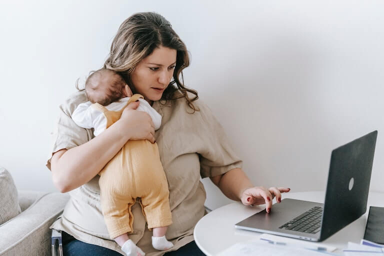 Mom on a laptop with a baby in her arms