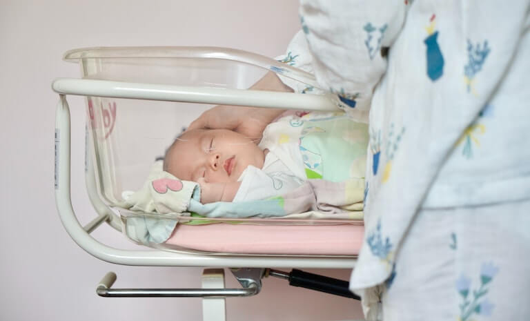 Newborn baby swaddled in hospital bed