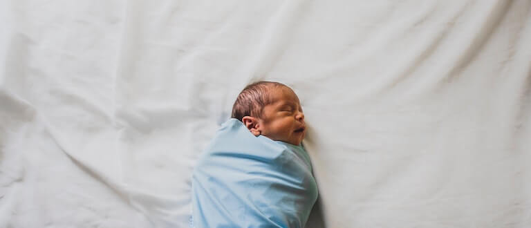 Newborn baby swaddled in blue
