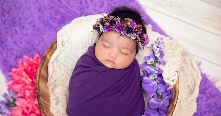 Swaddled baby girl in purple outfit