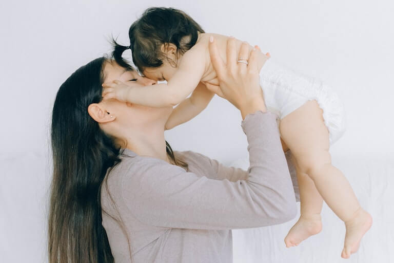Baby in a diaper being held by their mother
