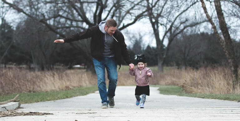 Dad running around outside with his small daughter