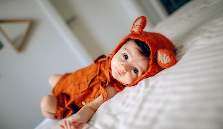 Baby in an orange outfit staring at you