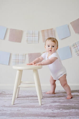 A small child leaning on a stool for support
