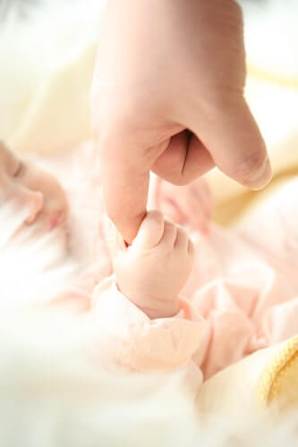 A newborn baby squeezing their mothers finger